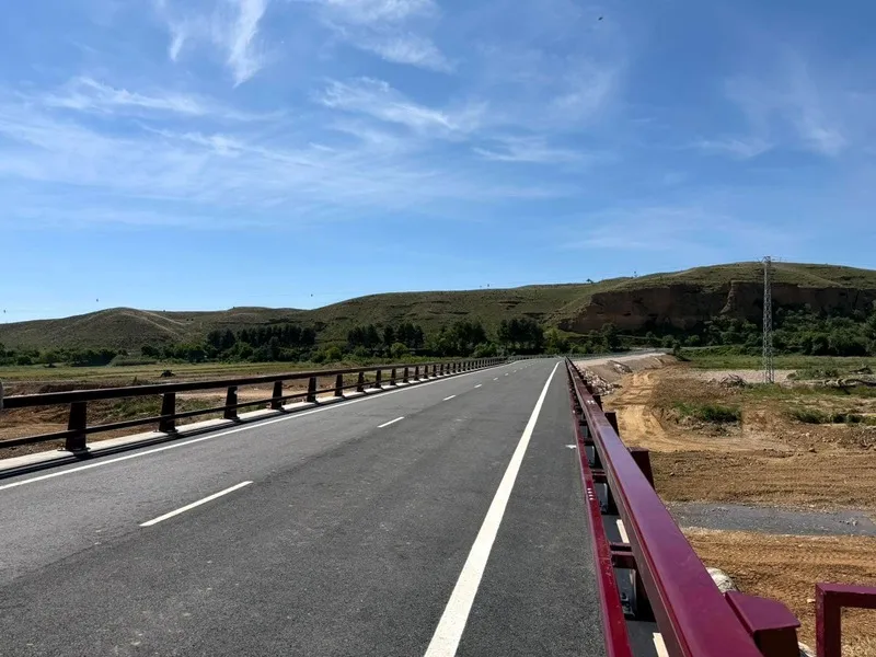 Vista panorámica del nuevo puente reconstruido en la carretera A-2306 sobre el río Cámaras, mostrando la calzada asfaltada de dos carriles y las barreras de seguridad.